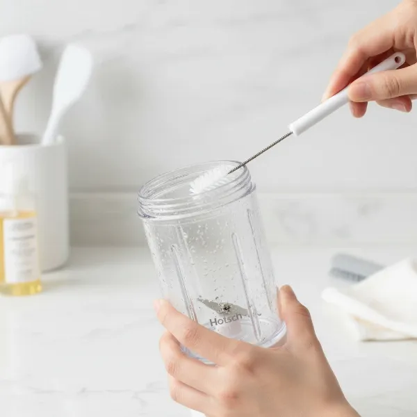 Hands cleaning the Hotsch portable blender with a small brush, illustrating the ease of maintenance and hygiene of the device.